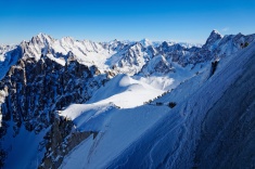 Skiers descend the snow ridge from Aiguille du Midi (3842m) down to the Vallée Blanche